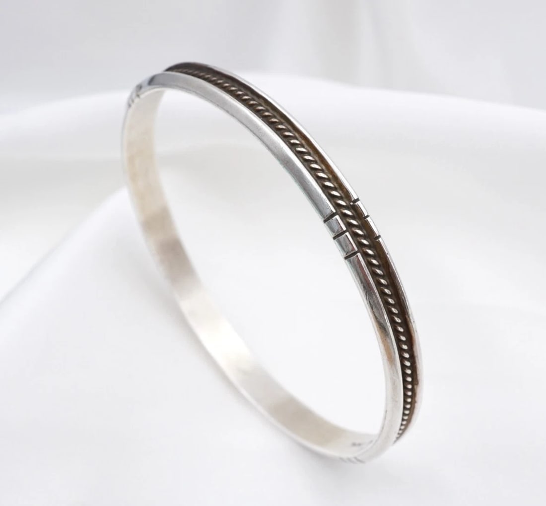 Navajo Sterling Silver Rope Bangle Bracelet Verna Tahe 8.2" Stamped 6.5mm BS3315: This bracelet from Navajo artisan Verna Tahe features a solid sterling silver bangle embellished with a continuous rope design in the center. Complete with stamped ribbed designs around the border, th