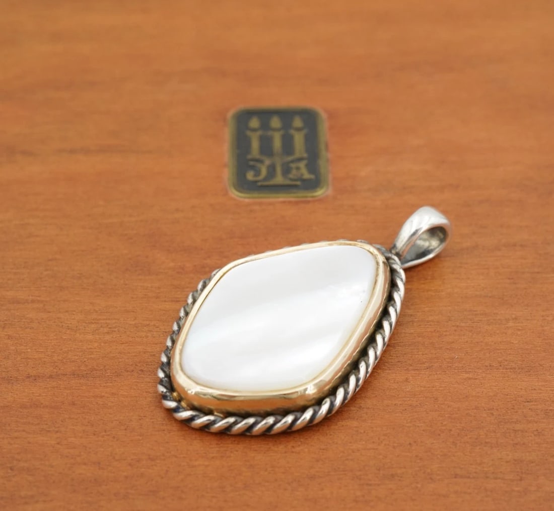 James Avery Alessandra Pendant Mother of Pearl Sterling 14k 1.5" Retired PS2429: This retired James Avery Alessandra pendant features a large slab of mother of pearl bezel set in rich 14k yellow gold and framed by an intricate sterling silver rope design. Metal Type: Sterling Silv