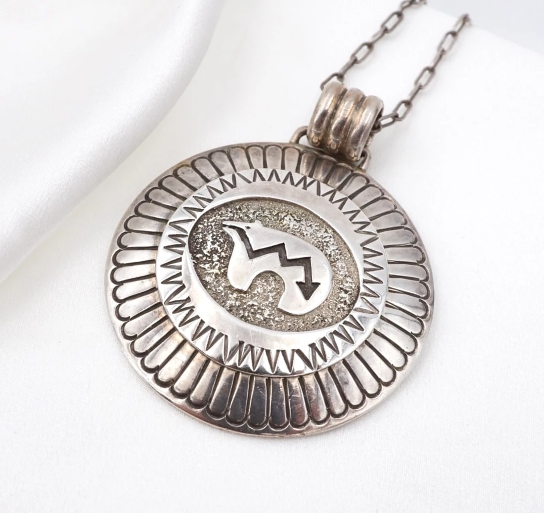 Henry Baca Spirit Bear Concho Pendant Necklace Sterling Silver 26" Navajo NS2369: This statement necklace from Navajo artisan Henry Baca centers on a large concho pendant embellished with a classic heart-line spirit bear design in the center. The concho is adorned with a textured b