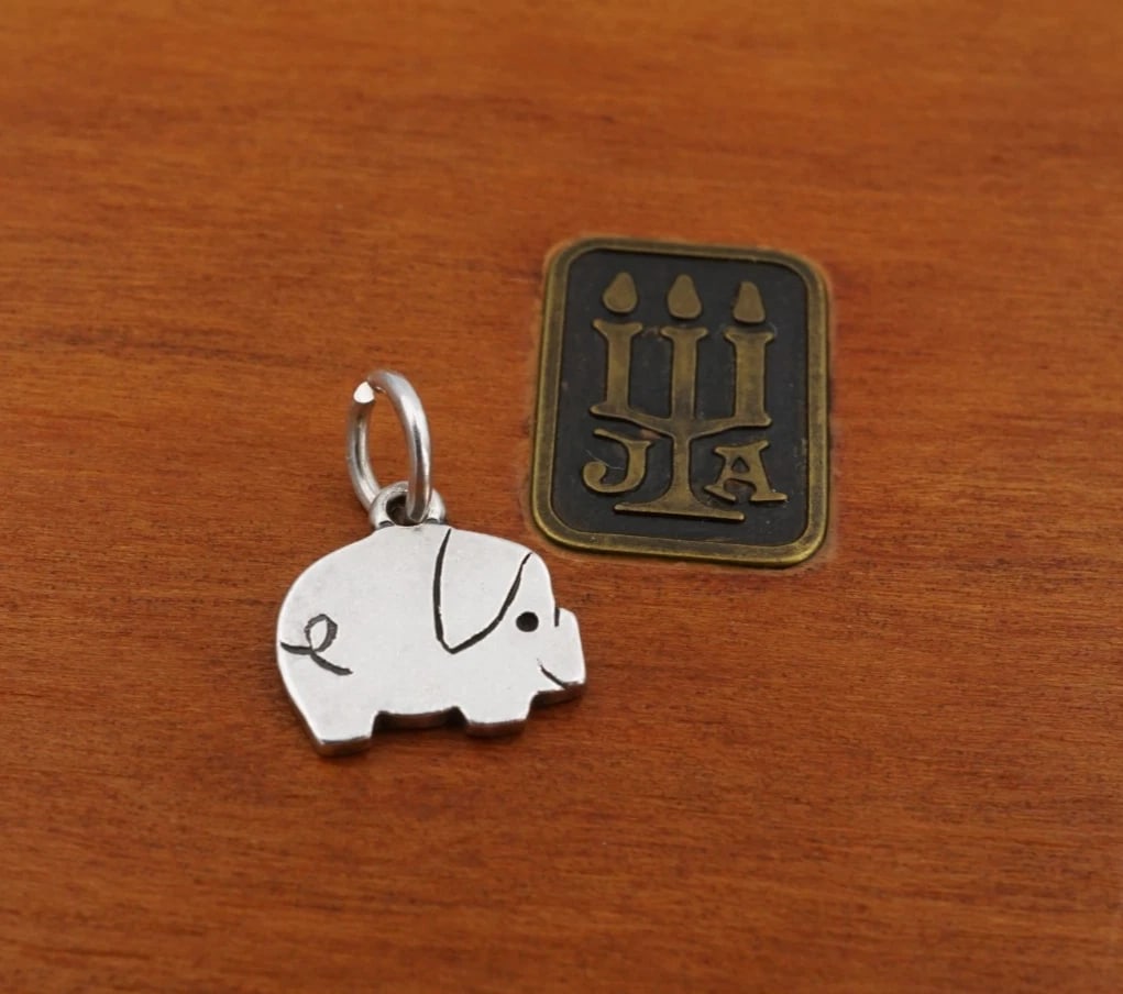 James Avery Flat Pig Charm Pendant Sterling Silver 0.44" Rare Retired CHS2386: This charm is a rare, retired James Avery design. It features a sterling silver pig motif with a curly tail, a large droopy ear, a solid black dotted eye. Metal Type: Sterling Silver Notable Marks: JA