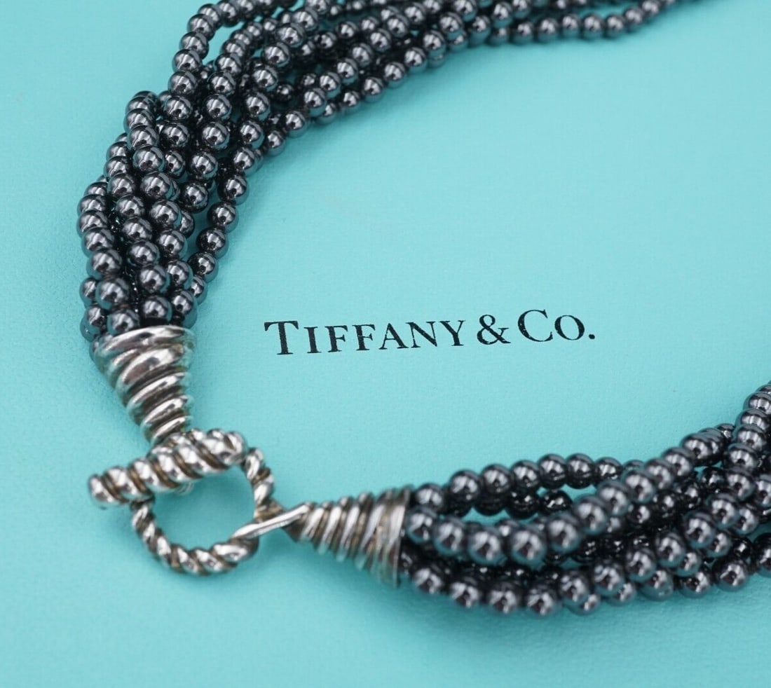 Tiffany Torsade Hematite Bead Necklace Sterling Silver Toggle 17" Folder NS2144: This necklace from Tiffany & Co. features 8 strands of lustrous hematite beads measuring in at 4 mm each with a sterling silver toggle clasp. Comes with folder. Metal Type: Sterling Silver (tested and
