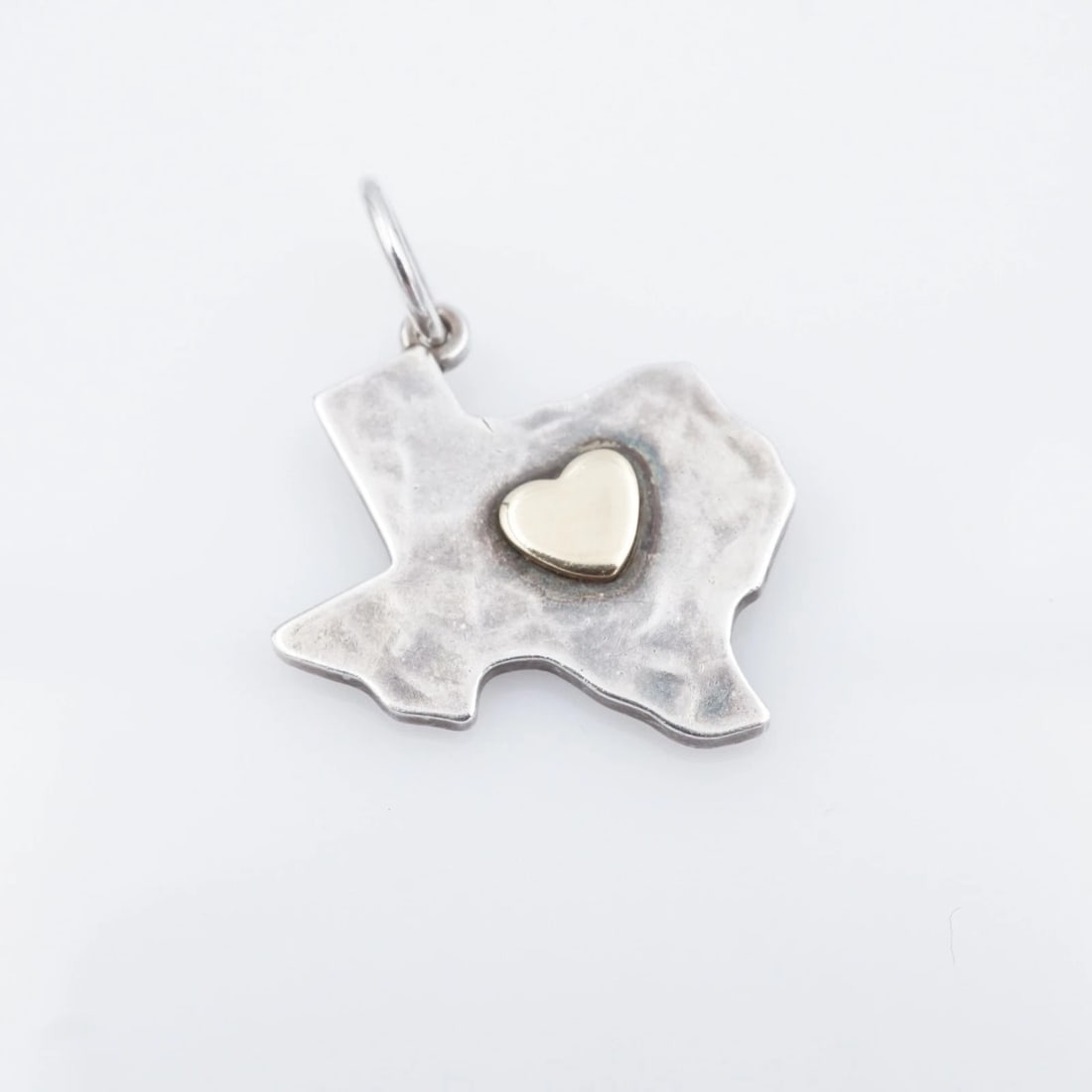 James Avery Hammered Deep Heart of Texas Charm Sterling 14k Retired CHS2220: This rare retired James Avery piece features a classic Texas shaped charm with a 14k yellow gold heart design in the center, and completed with a hammered texture. This sweet charm is a great way to d