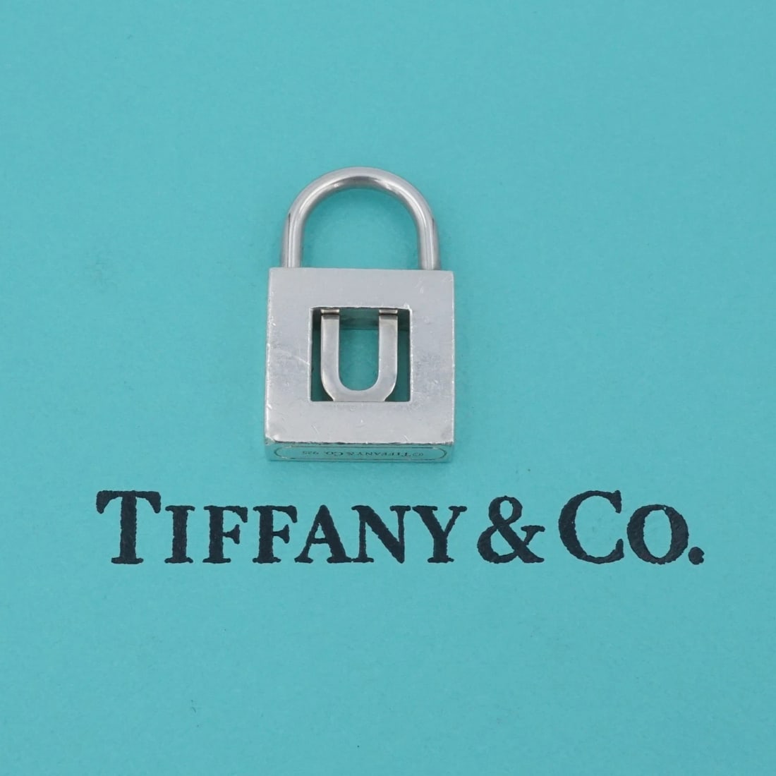 Tiffany & Co Letter U Lock Charm Initial Pendant Sterling Silver 0.9" PS2315: This retired Tiffany & Co. pendant features a classic padlock pendant with an openwork "U" cutout in the center. Crafted of solid sterling silver. Metal Type: Sterling Silver Notable Marks: Tiffany & 