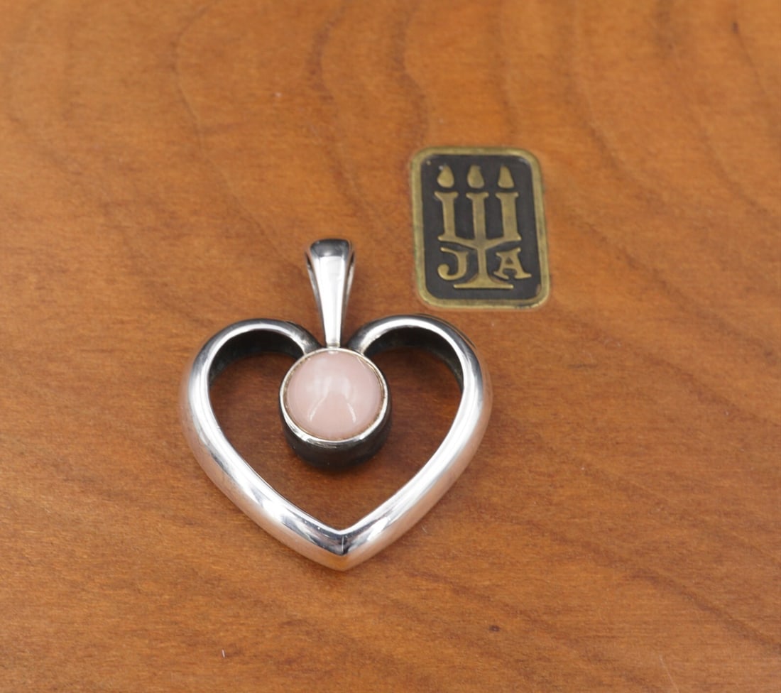 James Avery Pink Opal Open Heart Pendant Sterling Silver 1" Retired PS2013: This James Avery designer pendant features a simple open heart design with a bezel set pink opal in the center. This design has been retired and is no longer sold at James Avery retail locations. It w
