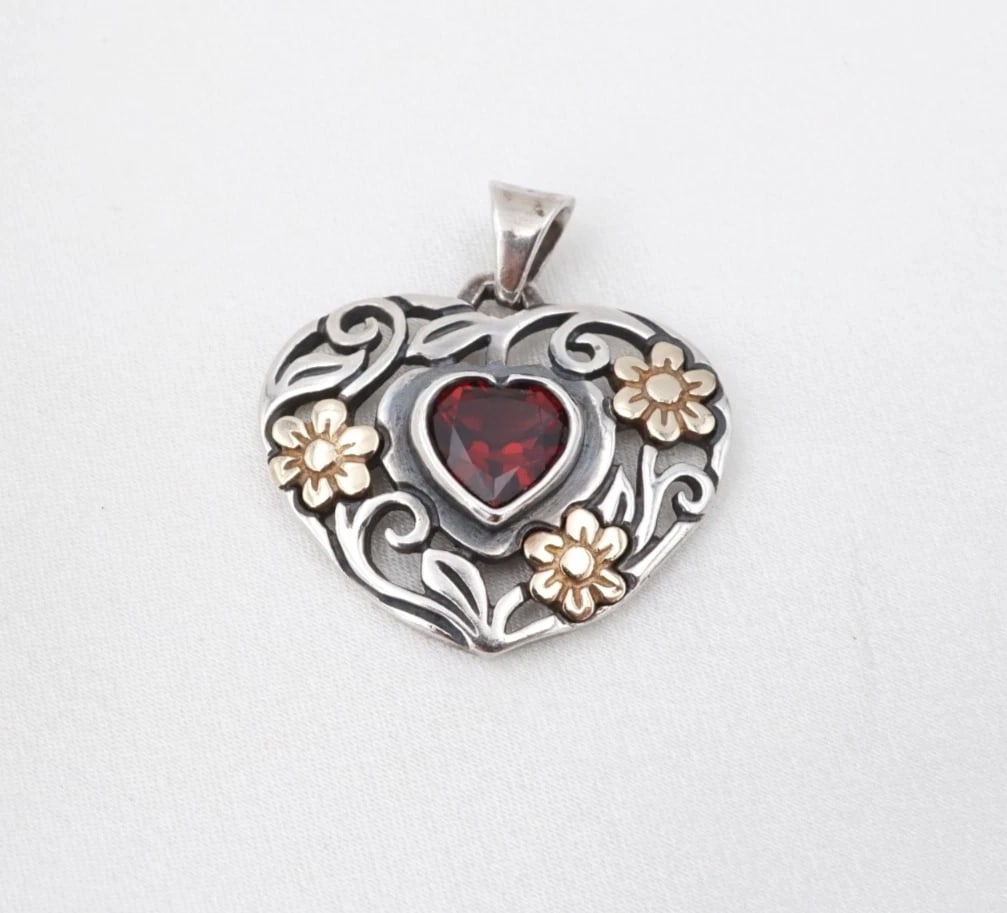 James Avery Floral Garnet Heart Pendant Sterling 14k Gold 1" Retired PS2406: This retired James Avery pendant features a vivid, heart shaped garnet bezel set atop an openwork sterling silver heart pendant embellished with filigree vines and 14k yellow gold flower motifs. Metal