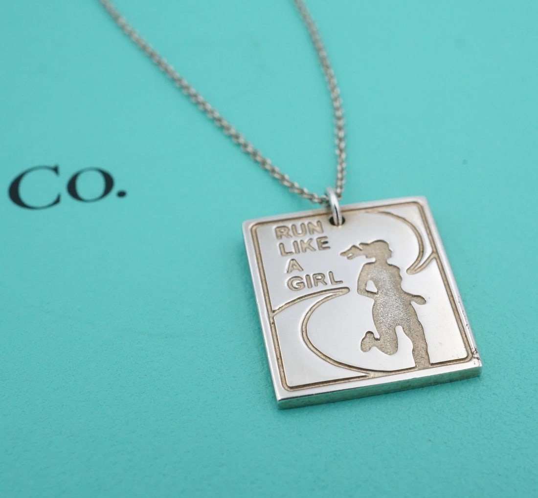 Tiffany & Co. Run Like A Girl Marathon Necklace Sterling Silver 16" 2009 NS2424: This Tiffany & Co. x Nike necklace features a sleek rectangular pendant etched with the silhouette of a running woman and the empowering phrase "Run Like A Girl." This design was a commemorative finis