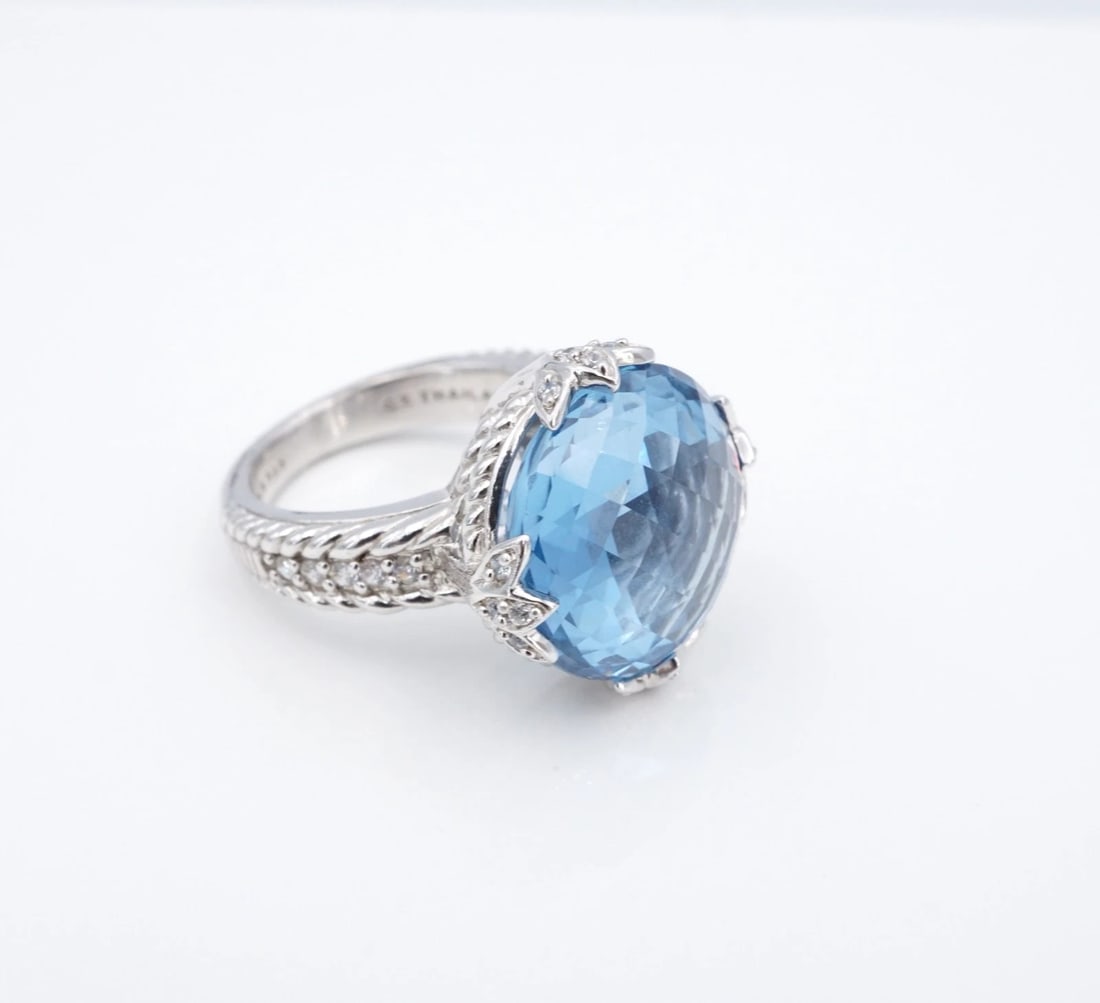 Designer Judith Ripka Blue Topaz Cocktail Ring CZ Sterling Silver Size 6 RS3975: This ring from designer Judith Ripka centers on a large blue topaz gemstone set in foliate prongs with round CZ accents. The gem is set atop a tapered sterling silver mounting with intricate rope deta