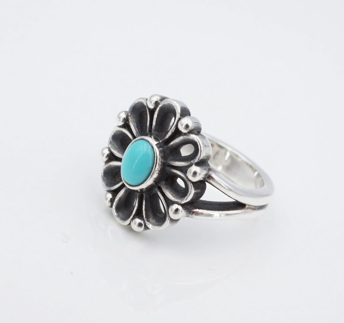 James Avery Turquoise De Flores Ring Sterling Silver Size 6.25 Retired RS4036: This James Avery "De Flores" ring centers on an oval shaped turquoise cabochon bezel set atop an ornate, openwork flower design with bead accents. Metal Type: Sterling Silver Notable Marks: JA Hallmar