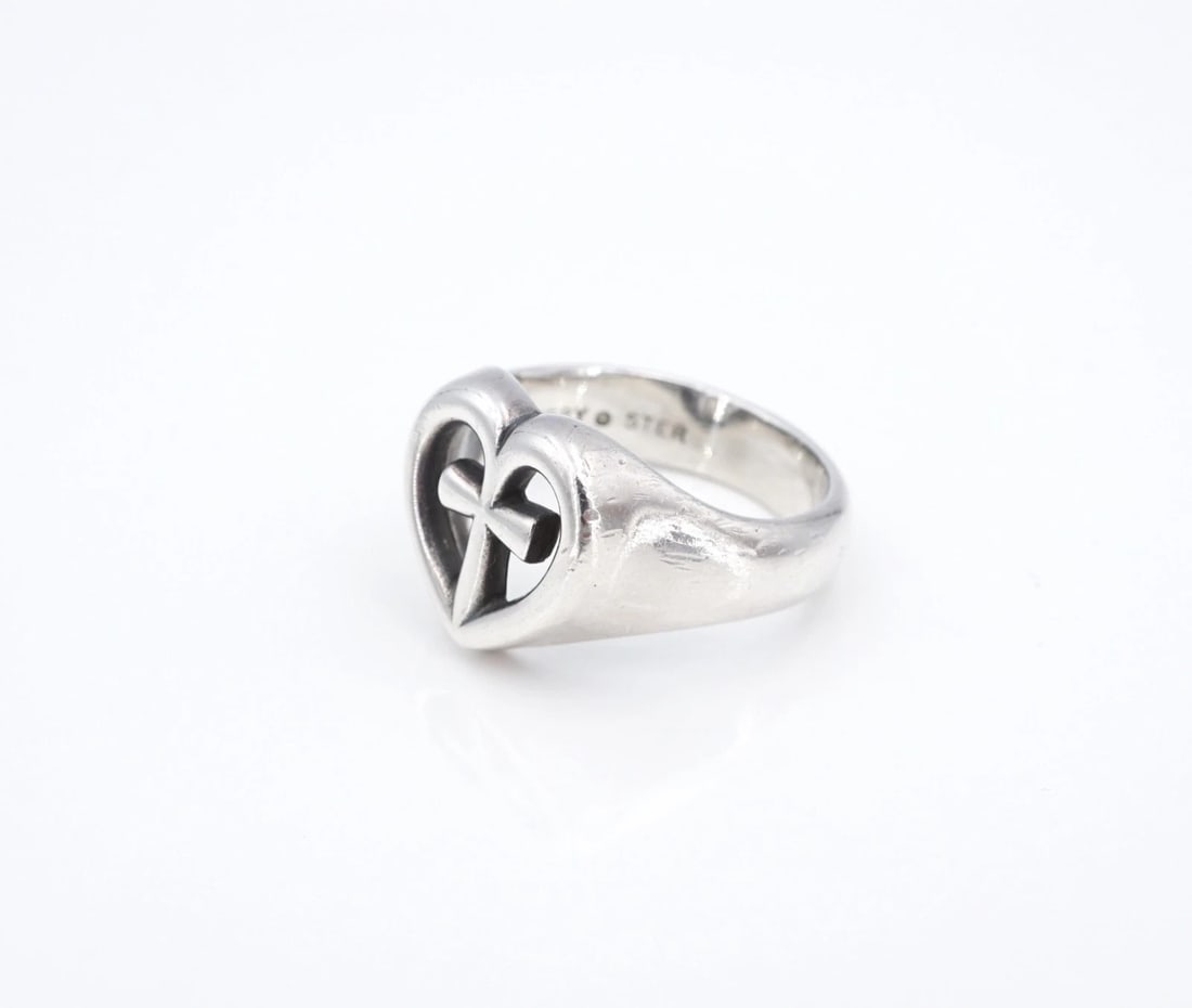 James Avery Eternal Love Heart Cross Ring Sterling Silver Size 6.25 Wide RS4027: This retired James Avery "Eternal Love Heart Cross Ring" centers on a wide, signet style band embellished with a cutout heart and cross design on the face. Metal Type: Sterling Silver Notable Marks: A
