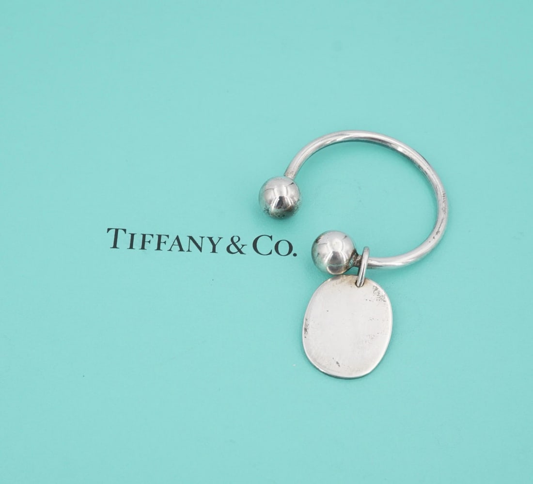 Tiffany & Co. Oval Tag Key Ring Sterling Silver Classic 2.8" Retired Rare M2099: This retired key ring from Tiffany & Co. features an oval-shaped sterling silver plate suspended from a large key ring with a screwball closure. Metal Type: Sterling Silver Notable Marks: Tiffany & Co
