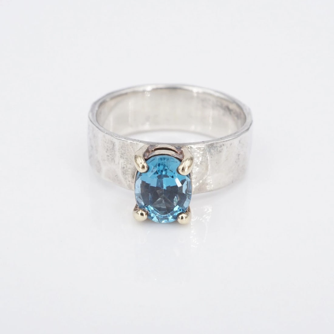 James Avery Julietta Blue Topaz Ring Sterling Silver 14k Gold Sz 6.5 RS3837: This "Julietta" ring from James Avery features a vivid blue, oval cut topaz high set in a 14k yellow gold basket atop a wide solid sterling silver band with a hammered texture. Metal Type: Sterling Si
