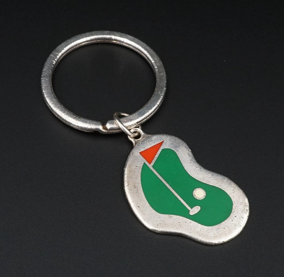 Tiffany & Co. Golf Course Key Ring Sterling Silver 1.5" Rare Enamel 1993 M2006: This vintage key ring from Tiffany & Co. features an asymmetrical enameled sterling silver plate with a putting green design in the center. Suspended from a large key ring. Metal Type: Sterling Silver