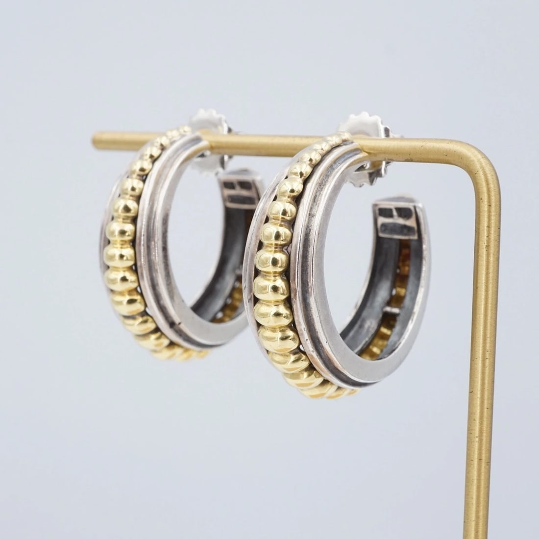 Lagos Caviar Graduated Bead Hoop Earrings Large Sterling Silver 18k 1.3" ES2843: This pair of Lagos Caviar earrings feature an oversized chunky sterling silver hoop design embellished with a row of graduated 18k yellow gold bead accents in the center. Metal Type: Sterling Silver &