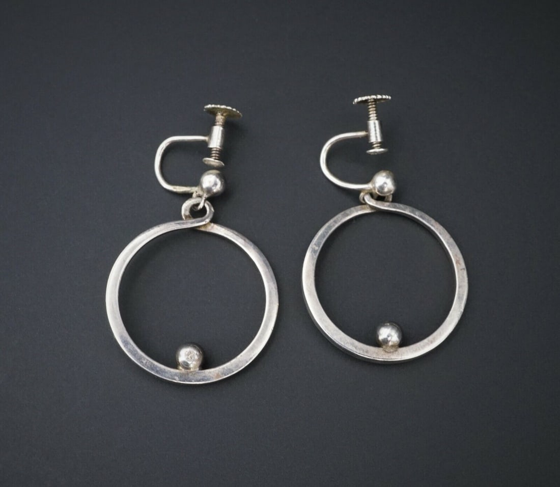 Modernist Sterling Silver Open Circle Bead Dangle Earrings Denmark BFO ES2069: This pair of sterling silver earrings feature an open circle design with a single silver bead resting on the inside rim of each circle. Metal Type: Sterling Silver (marked and tested) Notable Marks: B