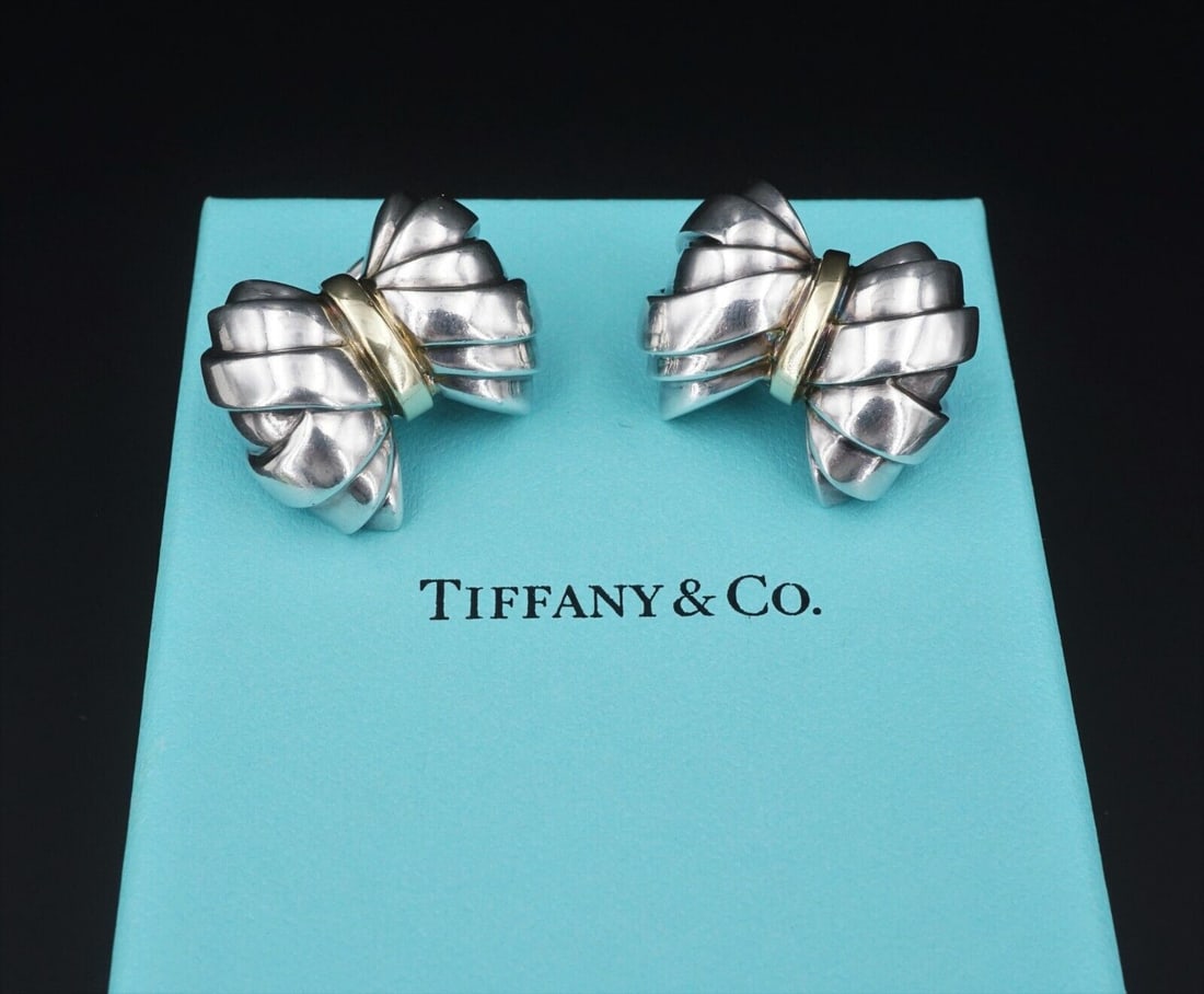 Tiffany Bow Ribbon Earrings Sterling Silver 18k Yellow Gold Clip ES2341: These statement earrings feature solid sterling silver folded ribbon bows, accented in the center in 18k yellow gold. The earrings fasten easily with clip-on closures for non-pierced (or pierced) ears