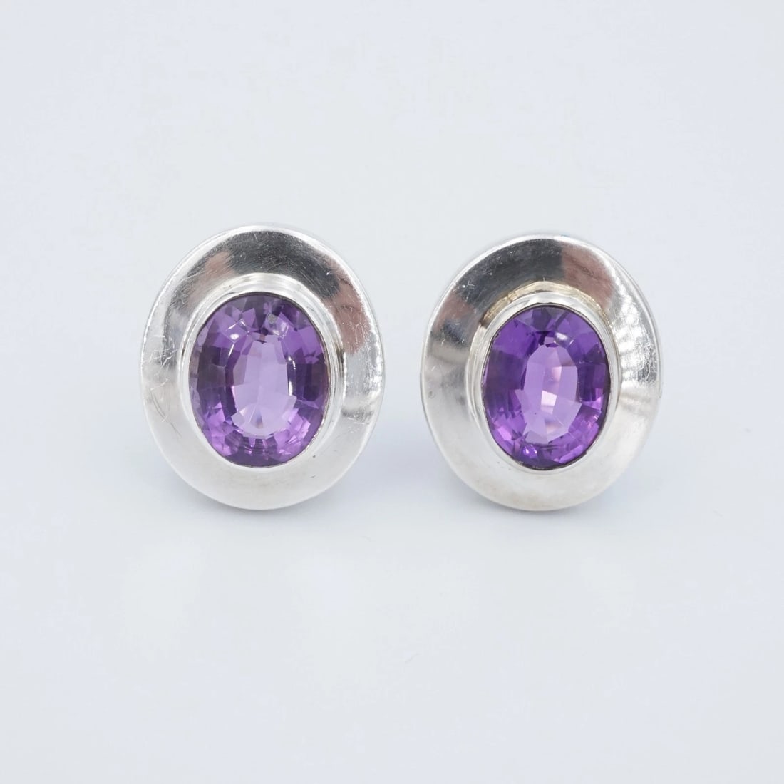 Burle Marx Earrings Sterling Silver Amethyst Clip-On Natural 1" Vintage ES2790: These clip-on earrings from designer Burle Marx each feature a vivid oval-cut amethyst gemstone bezel-set in an ovular frame crafted in solid sterling silver. Metal Type: Sterling Silver Notable Marks