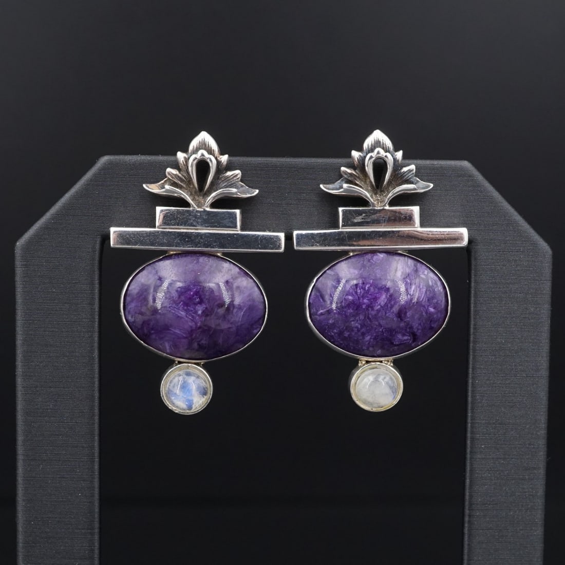 Tricia Young Charoite Moonstone Drop Earrings Sterling Silver 1.5" ES2750: These earrings from designer Tricia Young feature a large charoite gemstone bezel set beneath a modernist bar shape with an intricate fleur de lis design. With a moonstone cabochon at set at the base.