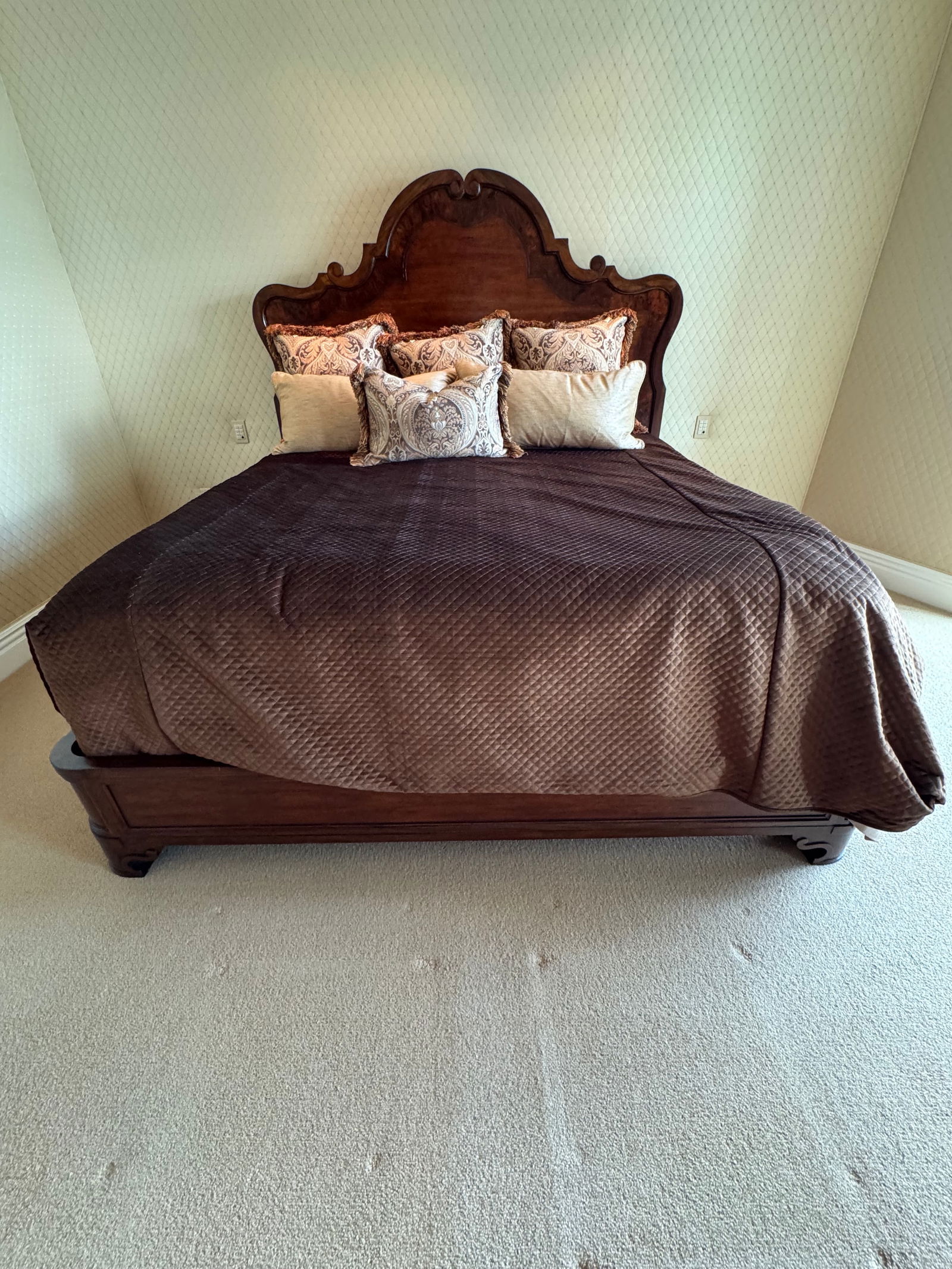 Ornate Carved Wood Queen Bed Frame with Decorative Headboard: Elegant wooden queen bed frame featuring a tall, ornately carved headboard with scrolled detailing and a warm polished finish. The bed showcases traditional craftsmanship with rich wood grain and soli