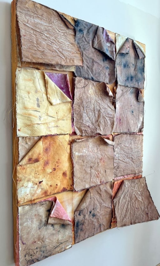 Diane Cooper Textile Collage Mixed Media on Canvas Abstract Contemporary Art: This striking mixed media textile collage by Diane Cooper showcases layered and stitched fabric squares in earthy tones, with subtle accents of yellow, pink, and indigo. Each fabric piece carries a se