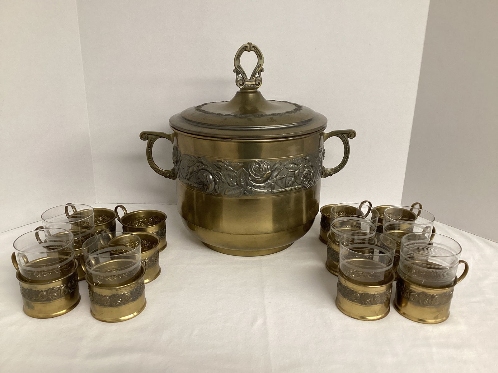 Vintage Brass Embossed Rose Pattern Eggnog Punch Bowl with Lid and 12 Brass Glass Holders: Bowl is 14" at handles, 10" diameter, 8" h at rim, 12 1/4" h overall, and lid is dented. The twelve holders have one glass that seems to fit correctly, six glasses that are a little too small, and no