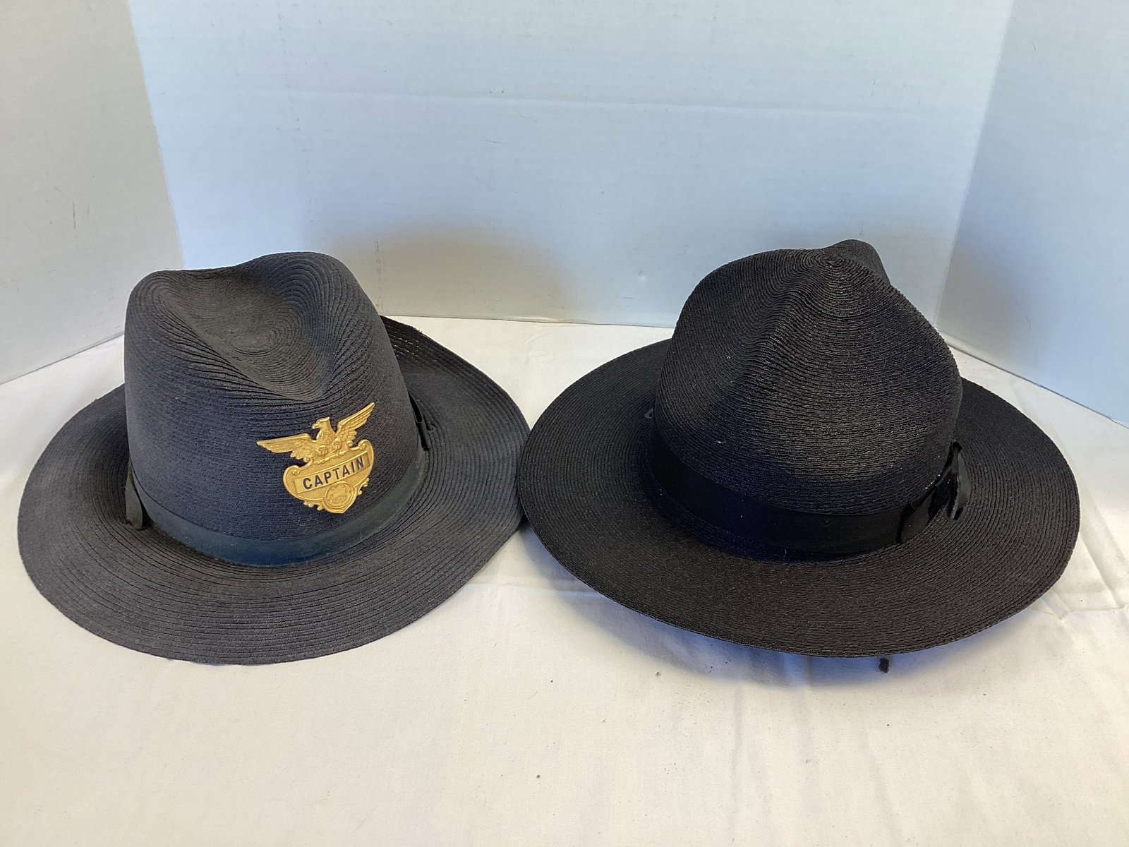 The Lawman Genuine Milan Navy and Black Hats: Navy has Captain badge and is size 7 5/8. Black is size 7 1/2 and has foam deterioration on the inside band. 