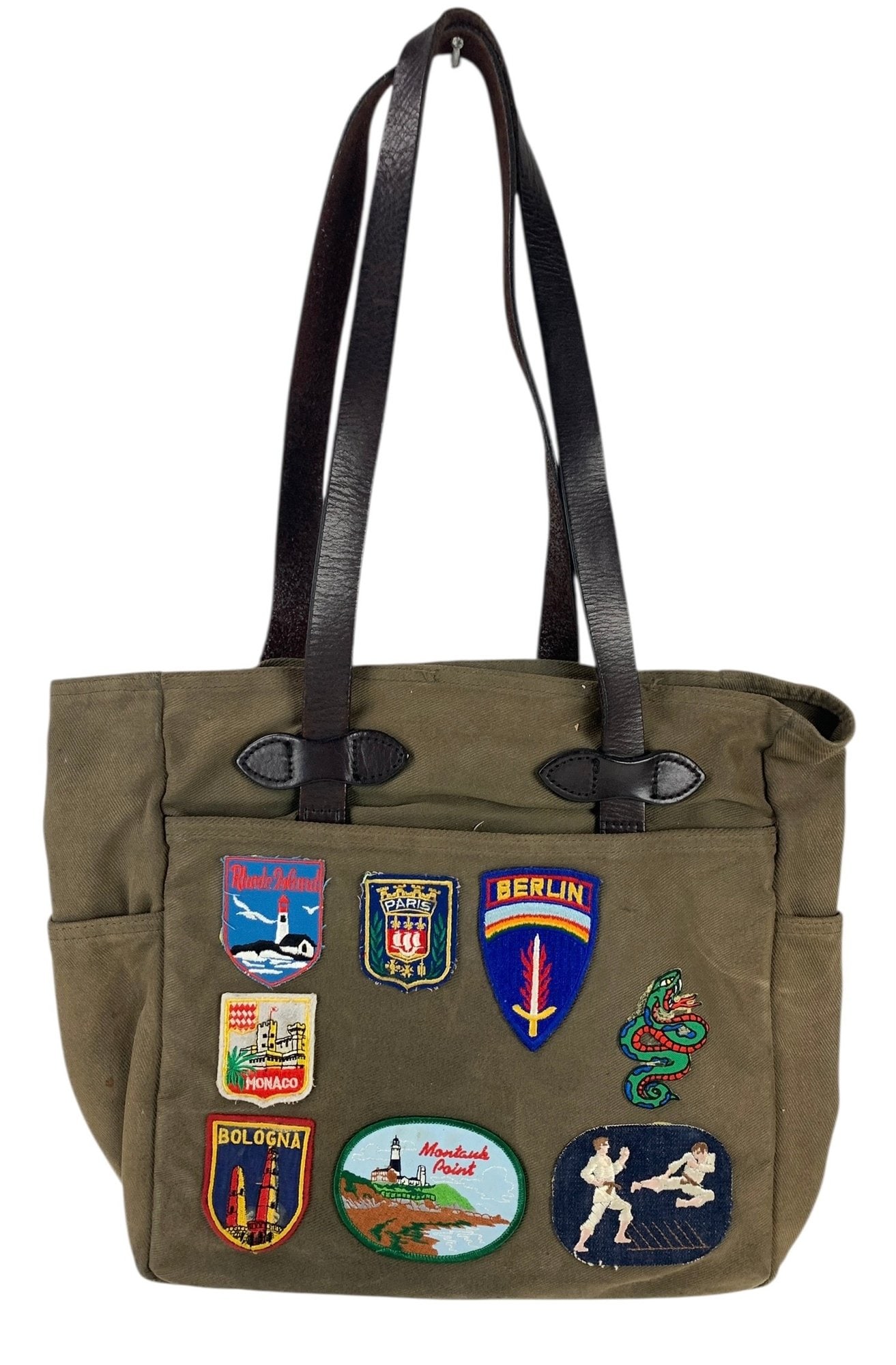 Filson Rugged Twill & Leather Tote Bag With Vintage Embroidered Patches - #S13-4: Made of water repellent, durable twill fabric, along with bridle leather handles. The tag on the inside the storm flap reads "A Genuine Filson 'Might As Well Have The Best' C.C. Filson Co. Seattle". C