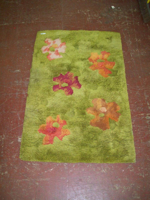 RUG: EDWARD FIELDS SIGNED PEA GREEN WITH FLOWER RUG. TEAR APPROX 5 INCHES FROM EDGE. LACKING PIECE ON EDGE. 72 INCHES HIGH X 46 INCHES WIDE