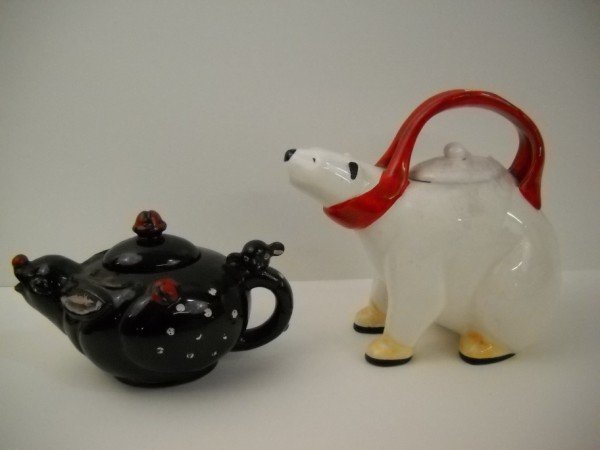 TEAPOTS: 2 TEAPOTS INCLUDING POLAR BEAR MARKED PELTZMAN DESIGNS. SCRATCHES; PAINT LOSS; MINOR CHIP ON BOTTOM OF BEAR PAW. LARGEST MEASURES 9 INCHES X 8 INCHES.