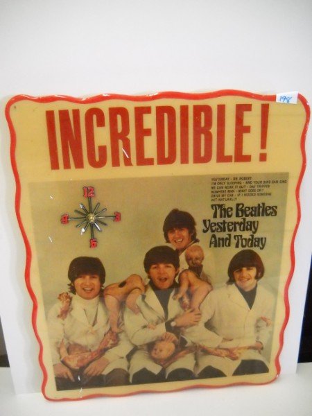 CLOCK: THE BEATLES YESTERDAY AND TODAY WOODEN BATTERY OPERATED CLOCK. CLOCK HANDS LACKING. 22 INCHES HIGH X 18 INCHES WIDE