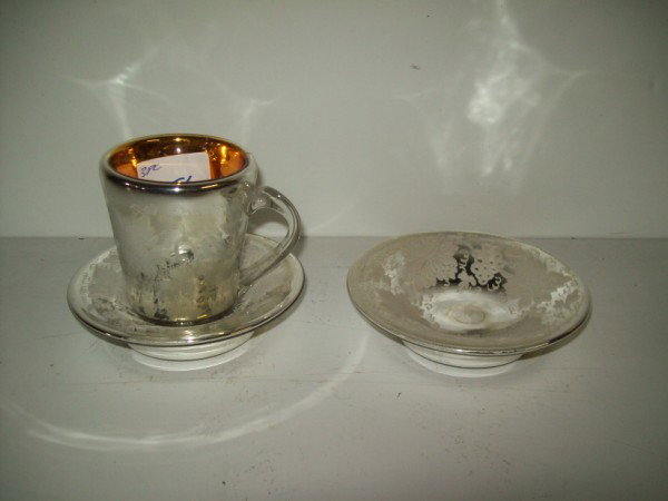 MERCURY GLASS CUP & SAUCERS: 3 PIECE MERCURY GLASS CUP & 2 SAUCERS. SCRATCHES. CUP MEASURES 3 1/2 INCHES HIGH X 4 INCHES WIDE; SAUCER MEASURES 5 INCHES DIAM