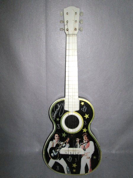 GUITAR: 1984 ELVIS PRESLEY TOY GUITAR. PAPER LIFTING; SCRATCHES; USED CONDITION. 29 INCHES X 10 1/2 INCHES.