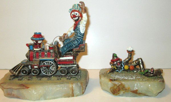 STATUE: 2 CLOWN STATUES BY RON LEE 1986 & 1984. REPAIR TO ARM; HAT LACKING TOP PIECE; PAINT LOSS. LARGEST MEASURES 7 1/2 INCHES X 8 INCHES.