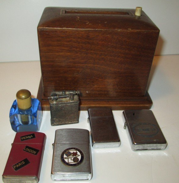 SMOKING LOT: COLLECTION OF 6 CIGARETTE LIGHTERS & 1 CIGARETTE DISPENSER. INCLUDING 2 ZIPPO (1 U.S.S. ENTERPRISE CVAN-65), 1 PENGUIN, 1 AUSTRIA CHAMP, 1 BLUE GLASS, 1 MADE IN U.S.A. USED CONDITION; HAIRLINE CRACK; 