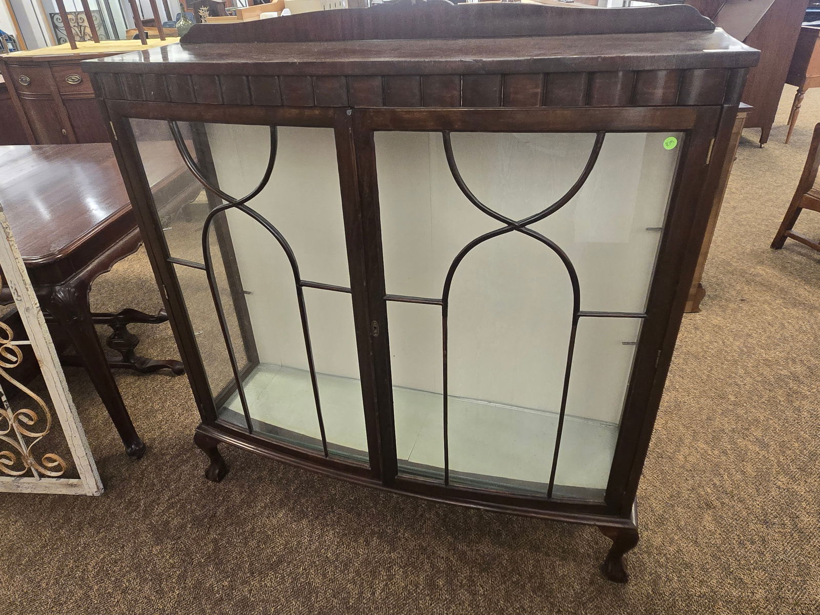 Mahogany curio cabinet: Mahogany curio cabinet. Ball and clawfoot legs. Glass shelves curved front doors w/fretwork. Chippendale feet