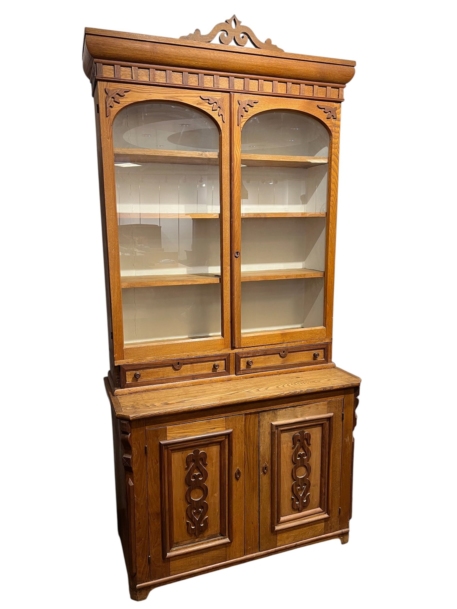 Victorian Eastlake Period Oak Stepback Cupboard: The antique furniture in the image is a Victorian Eastlake style cupboard or bookcase, likely dating from the late 19th to early 20th century. This two-piece "step-back" design typically features a gl