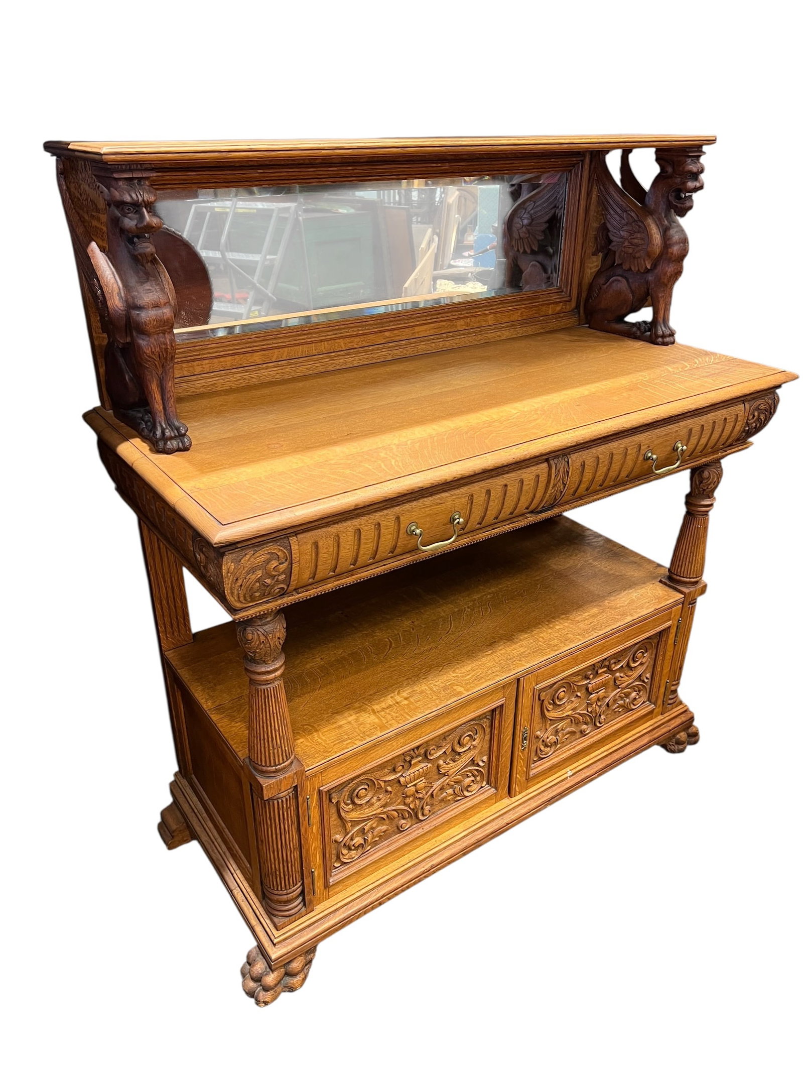 Victorian Style Carved Oak Sideboard: This is a late 19th-century American oak sideboard, likely crafted by R.J. Horner & Co. around the 1890s, featuring prominent carved winged griffin supports and a beveled mirror. [1, 2]Design Details: