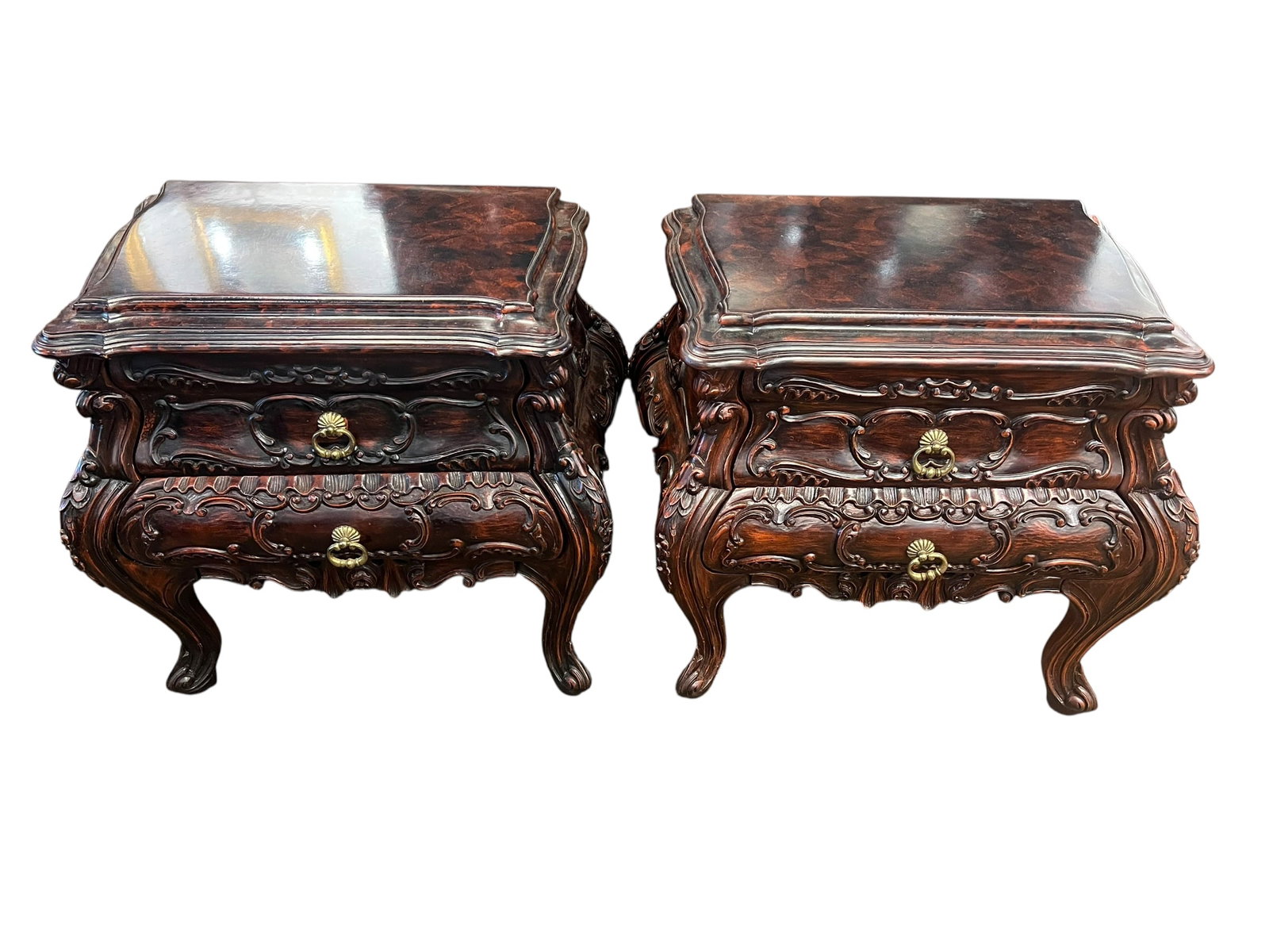 Pair of Walnut Bombay Nightstands: This image displays a matching pair of French Rococo style bombé nightstands (also classified as commodes or accent chests) featuring highly detailed, hand-carved decorative elements. [1]Key