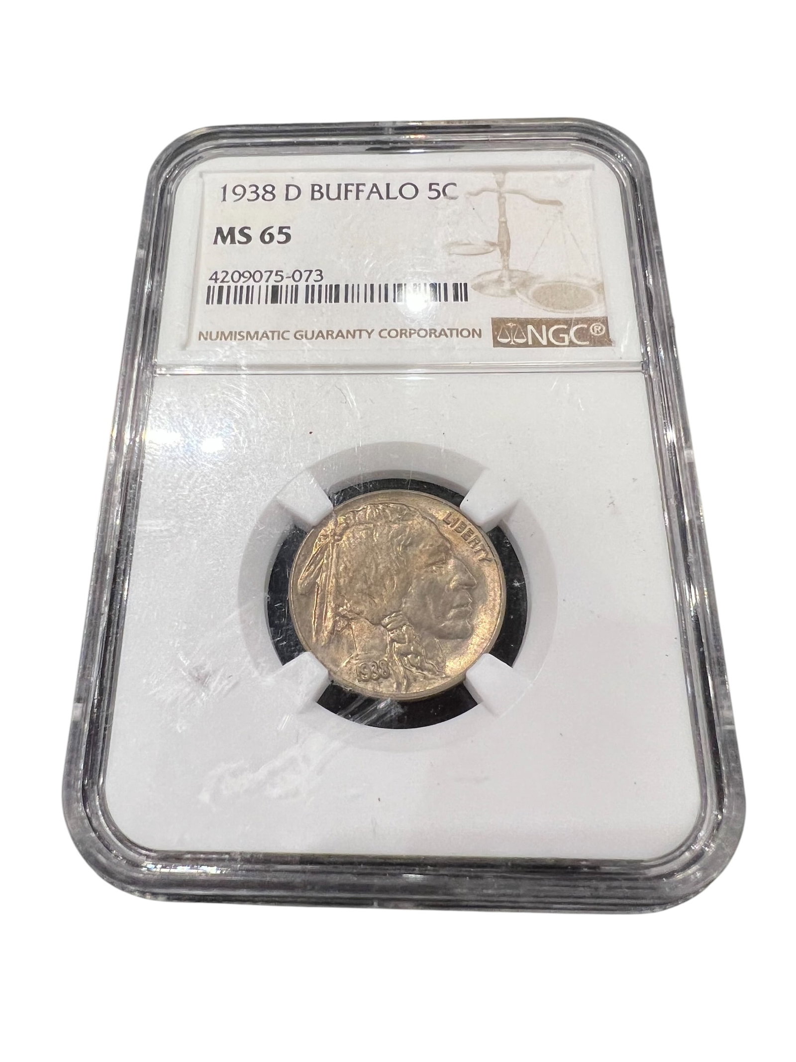Graded Buffalo Nickel: This is a graded 1938-D Buffalo nickel certified by the Numismatic Guaranty Company (NGC) as Mint State 65. [1, 2]Year and Mint: The coin was minted in 1938 at the Denver Mint ("D" mint mark).Grade: