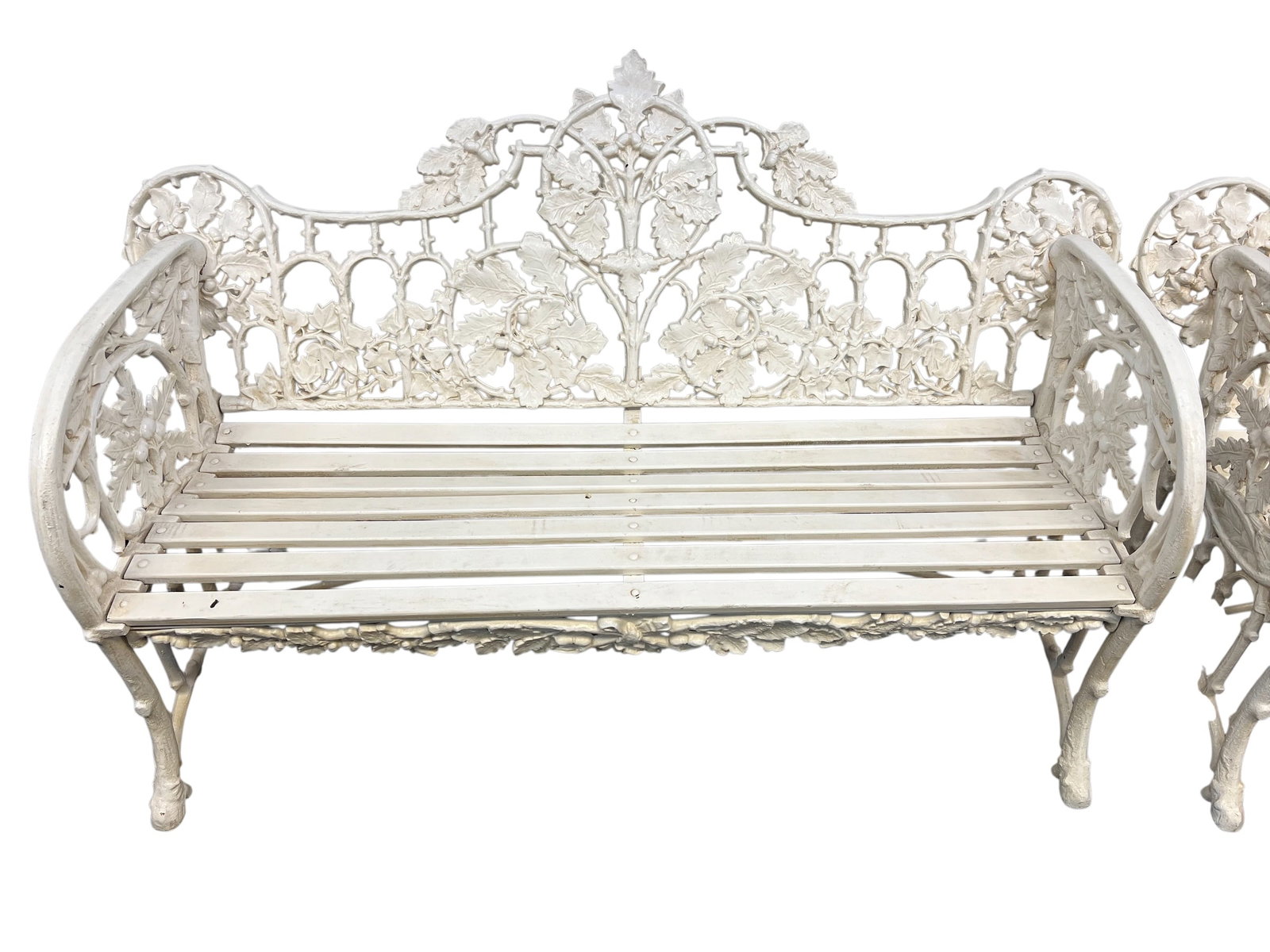 Cast iron bench: Victorian-style white cast iron garden bench with intricate oak leaf and acorn detailing.This style is often attributed to or inspired by the Coalbrookdale Foundry, known for ornate 19th-century cast 