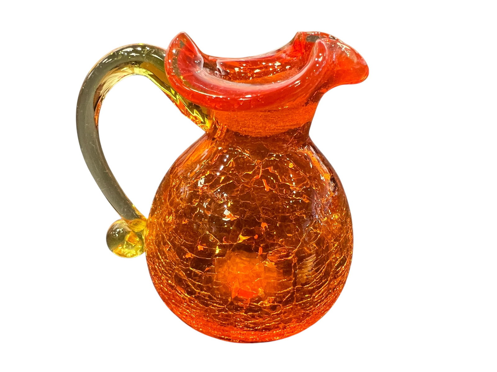 vintage Amberina orange crackle glass pitcher: This is a vintage Amberina orange crackle glass pitcher featuring a yellow applied handle.The piece is hand-blown and characterized by a textured, crackled surface created by dipping hot glass into co