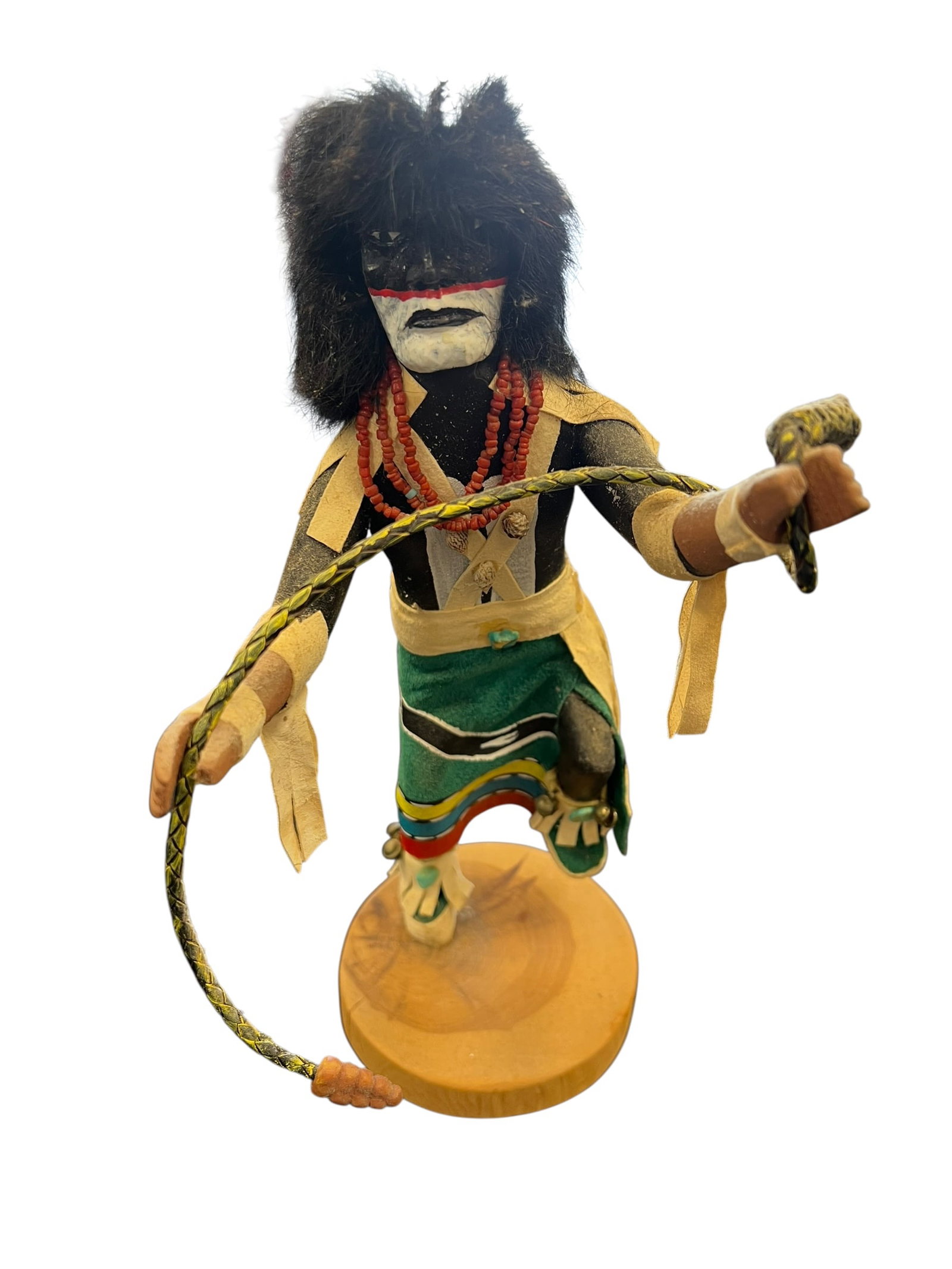 Hand Carved Hopi Kachina Doll: This is a vintage Chakwaina Warrior Kachina dancer figurine featuring black fur and a woven whip.The hand-painted doll is designed with a green skirt and red beaded necklace.These figures are