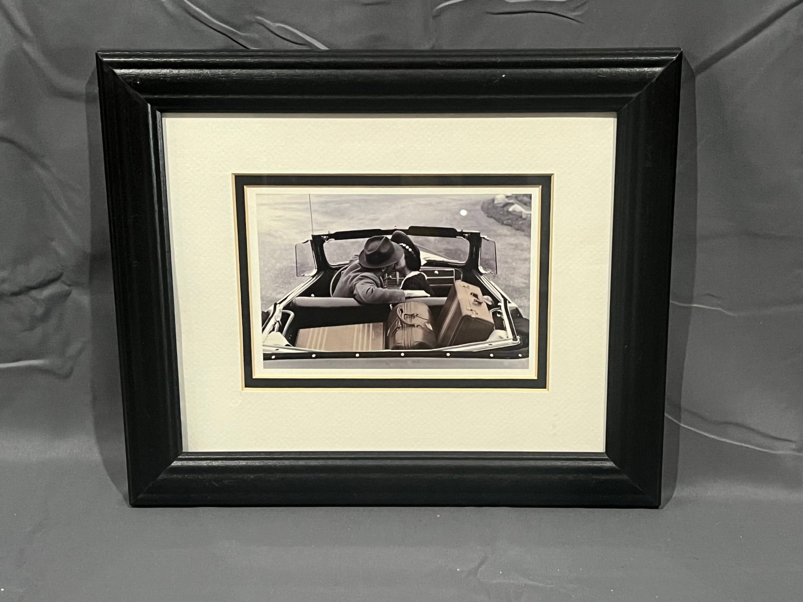 190“Weekend Getaway?? Print: This is a beautifully styled black-and-white art piece featuring a classic vintage photograph.Artwork DetailsThe framed photograph captures a romantic, cinematic scene from a bygone era:The Scene: A