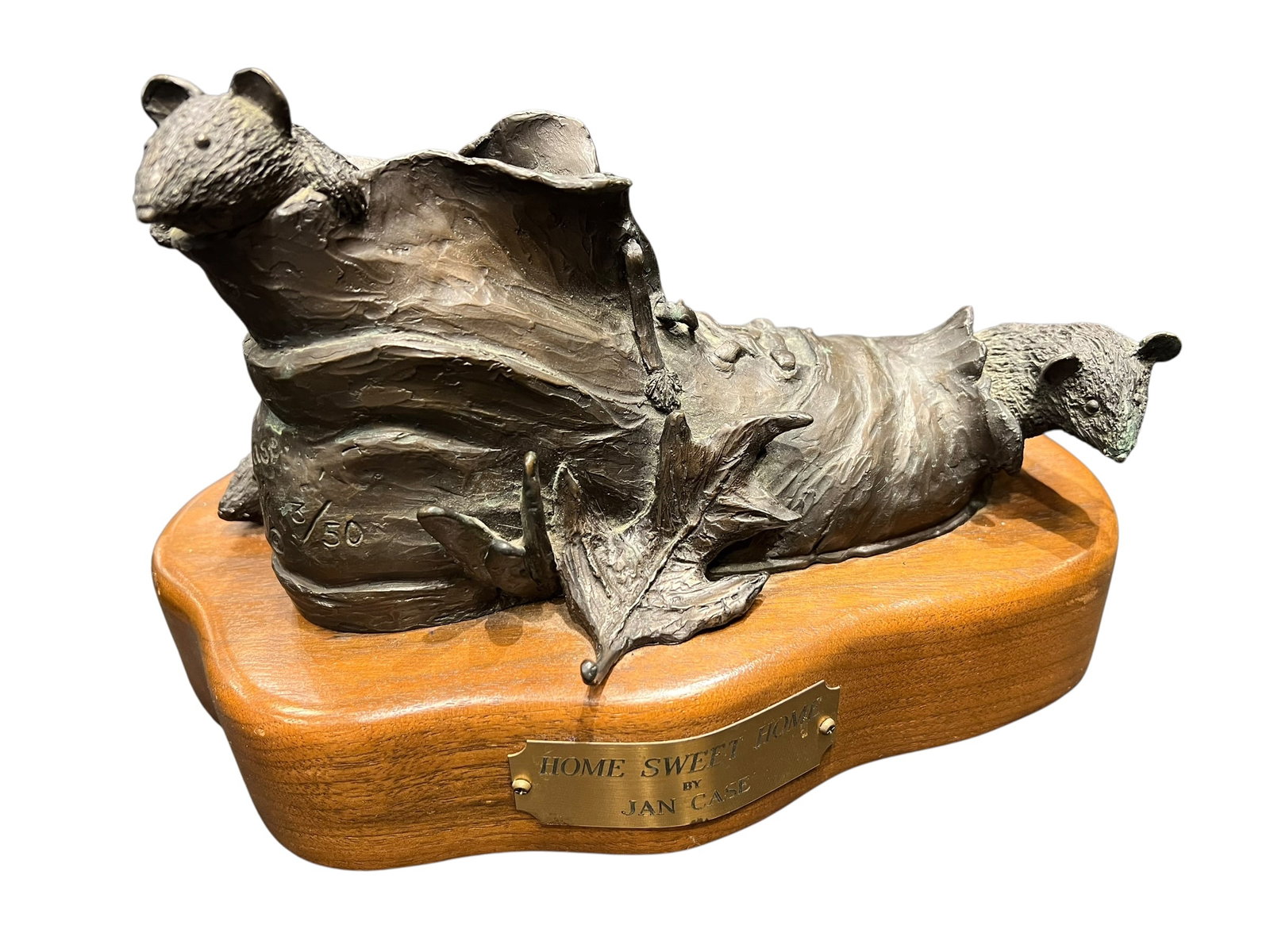 Bronze Figural Piece on Wooden Base: The image shows "Home Sweet Home," a limited-edition bronze sculpture by Jan Case depicting mice peeking out from a worn boot mounted on a wooden base with an engraved brass plaque.Artwork Title: