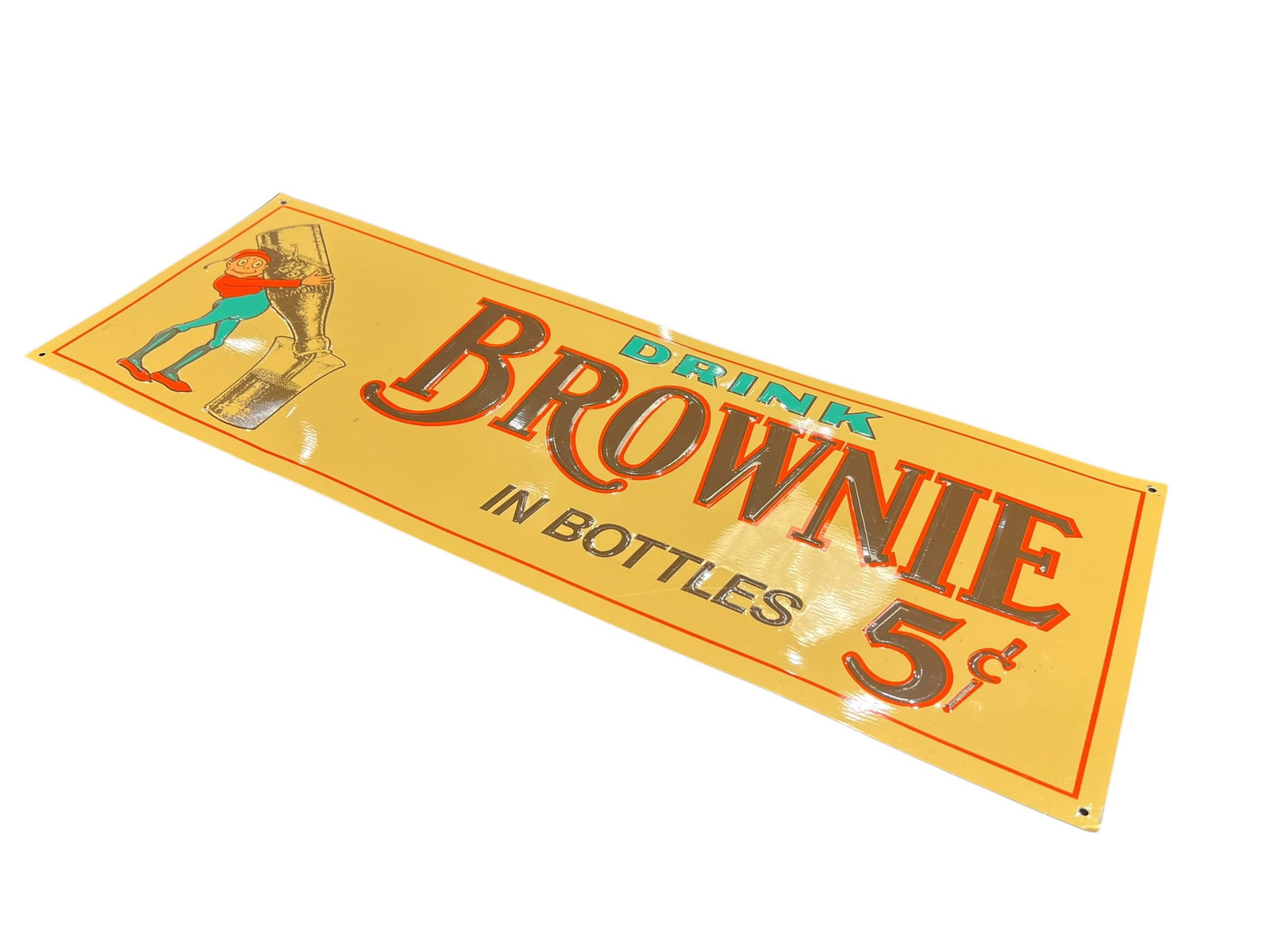 Brownie Metal Advertising Sign: This is a embossed single-sided tin advertising sign for Brownie Chocolate Soda from the mid-20th century, typically measuring around 21" x 7.5" and manufactured by The Burdick Company. [1, 2, 3]Item: