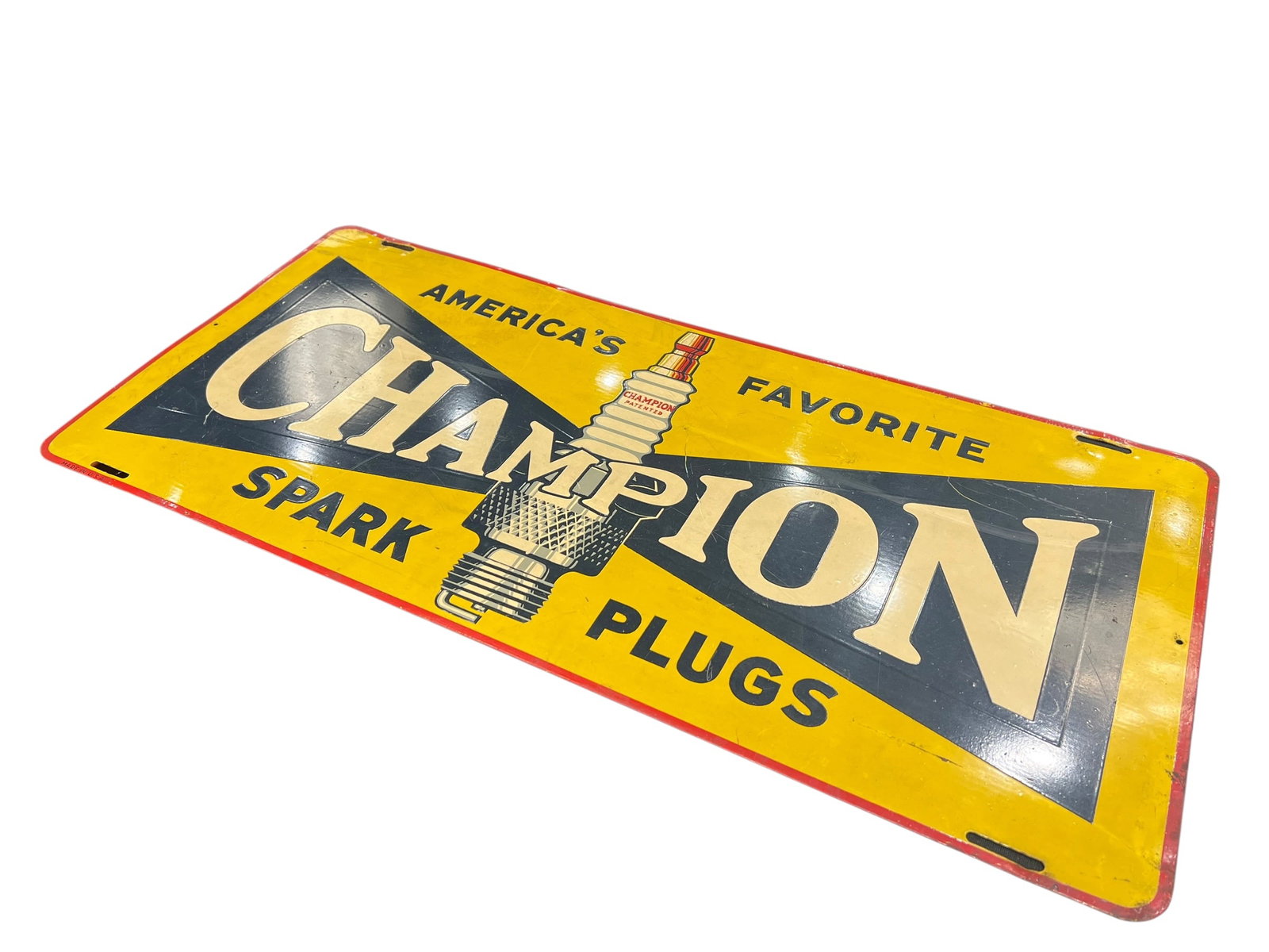 Champion Spark Plug Metal Advertising Sign: This is a single-sided tin or porcelain advertising sign for Champion Spark Plugs, featuring the classic "America's Favorite" graphic and centered spark plug illustration commonly produced during the 