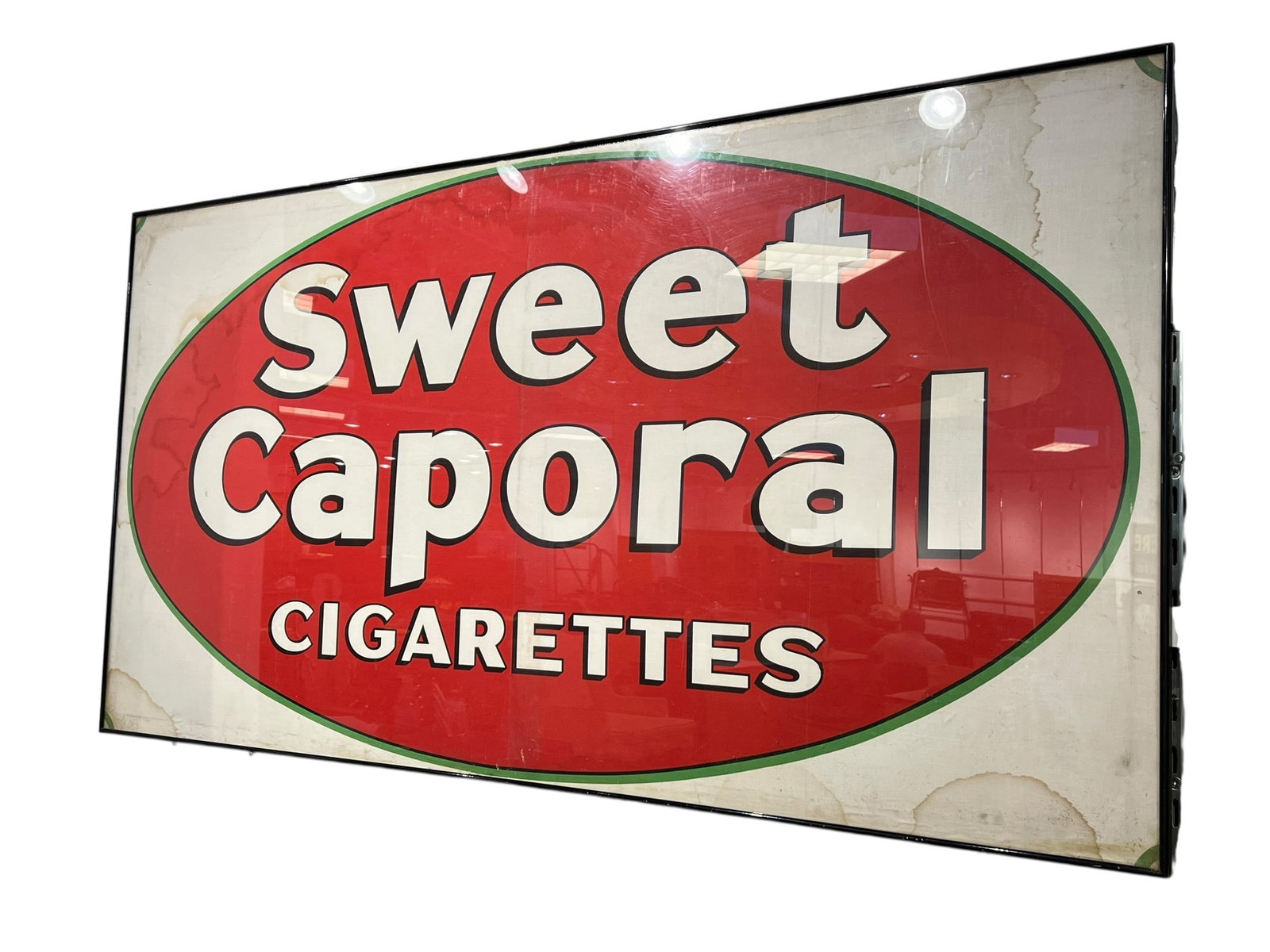 Sweet Caporal Cigarettes Advertising Poster: This vintage single-sided cardboard sign features the classic red and green oval branding for Sweet Caporal Cigarettes, a popular tobacco brand produced by the Imperial Tobacco Company in Canada