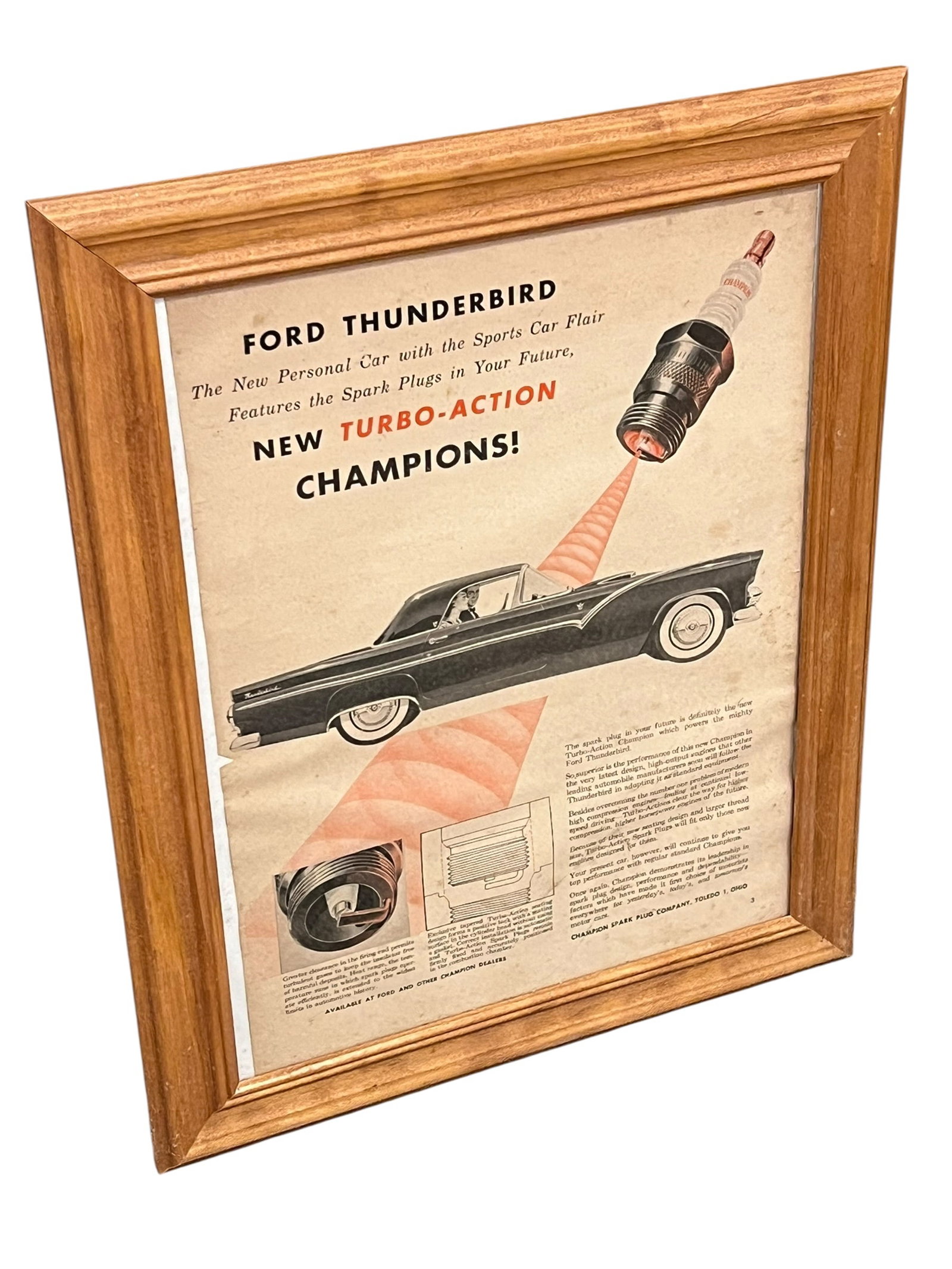 Thunderbird Advertising Poster: This framed vintage magazine advertisement from late 1954 showcases the newly introduced Ford Thunderbird paired with Champion Turbo-Action spark plugs. [1]Subject: An original promotional print