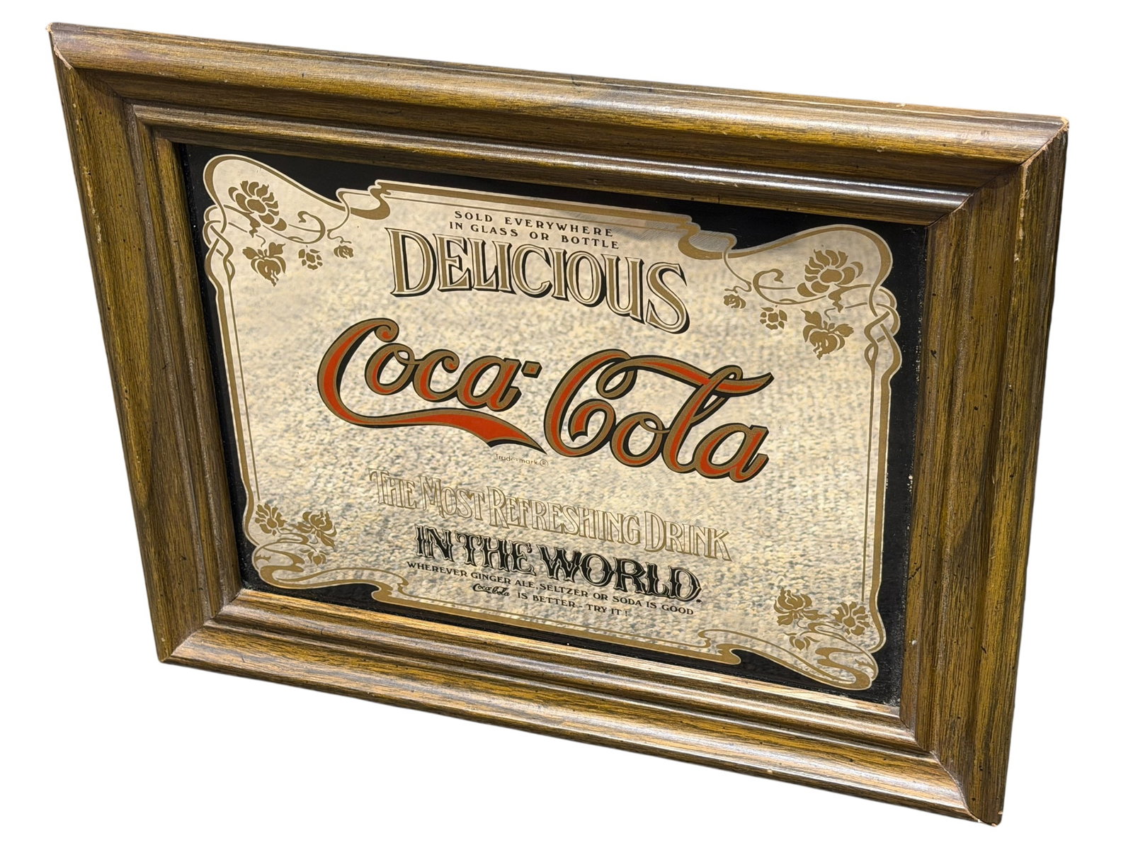 Coca Cola Mirrored Advertising Sign: This is a vintage 1970s–1980s Coca-Cola reverse-painted advertising mirror featuring the "Delicious Coca-Cola / The Most Refreshing Drink in the World" slogan in a distressed wooden frame. [1, 2]Des