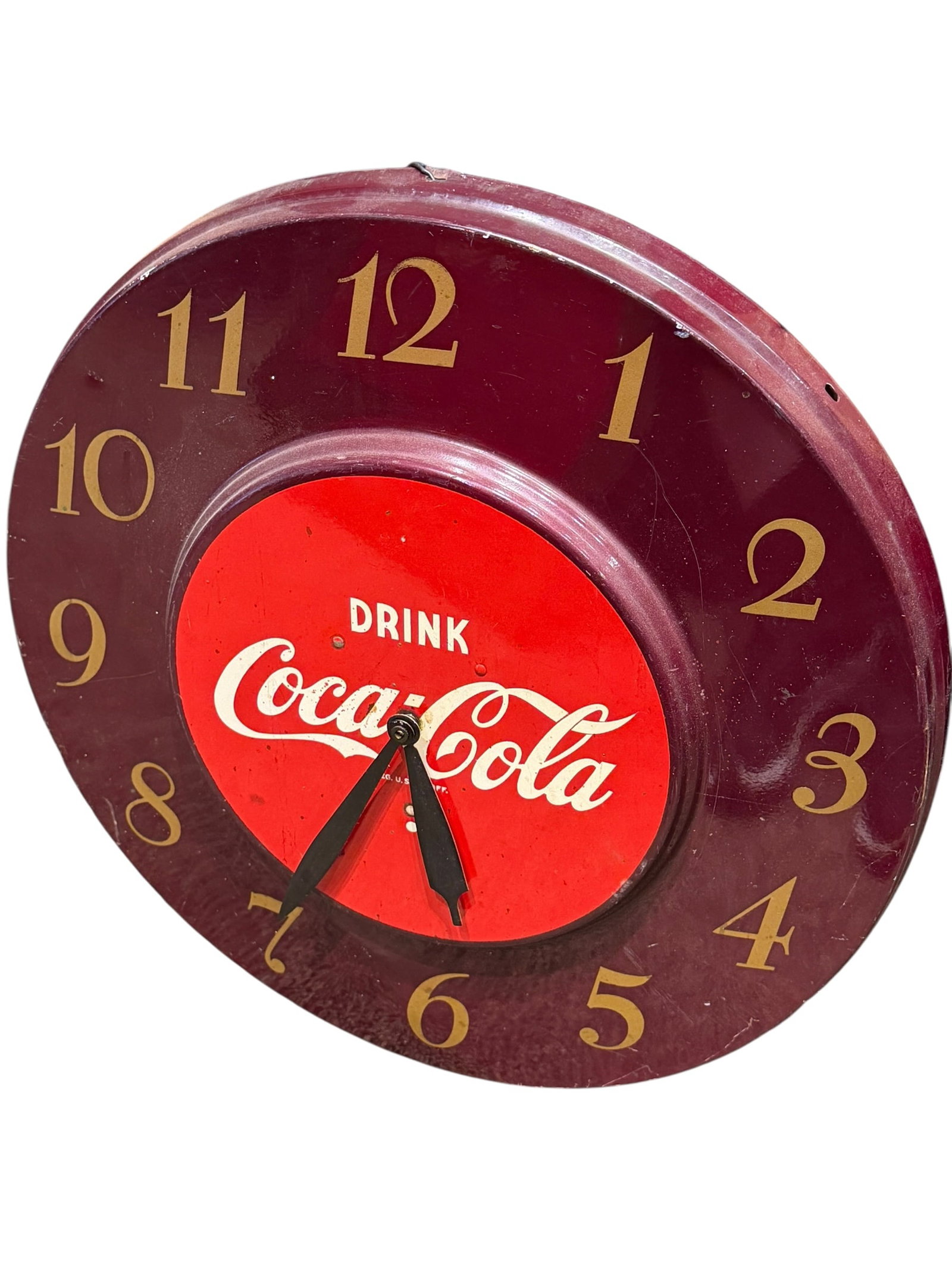 Early Coca Cola Electric Clock: This is a vintage 1950s Coca-Cola advertising wall clock featuring an oxblood/burgundy outer rim with gold raised numbers and a bright red center dial with the classic white "Drink Coca-Cola" script