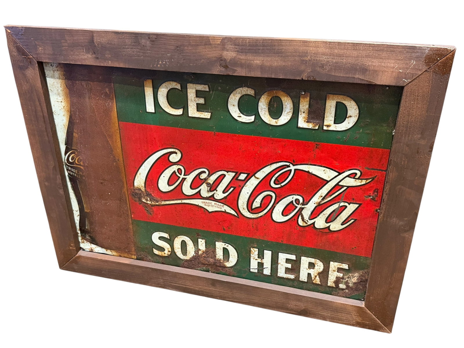 Early Coca Cola Advertising Sign: This framed 1989 Coca-Cola metal sign features a distressed red, green, and white "Ice Cold Sold Here" graphic with a classic wooden frame. [1, 2]Item: Official 1989 Coca-Cola "Ice Cold Sold Here"